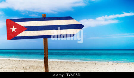 Kuba Flagge auf hölzernen Tisch am Strand Hintergrund. Es liegt am Strand und klares Wasser von Meer und blauer Himmel im Hintergrund. Stockfoto