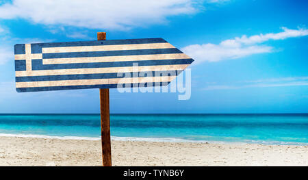 Griechenland Flagge auf hölzernen Tisch am Strand Hintergrund. Es liegt am Strand und klares Wasser von Meer und blauer Himmel im Hintergrund. Stockfoto