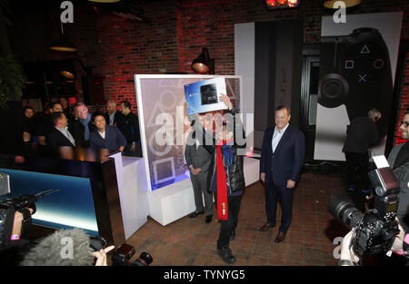 Der Präsident und CEO von Sony Computer Entertainment of America, Jack Tretton, President und Group CEO von Sony Computer Entertainment, Andrew House watch 24-jährige Joey Chiu aus Brooklyn reagieren, wenn er der Erste ist die neue PlayStation 4 auf einer Party zu kaufen feiert die Einführung der Sony PlayStation 4 in New York City am 14. November 2013. PlayStation kündigte auch eine begrenzte Anzahl von Einheiten für den Verkauf wird bei der Veranstaltung am 15. November verfügbar sein. UPI/John angelillo Stockfoto