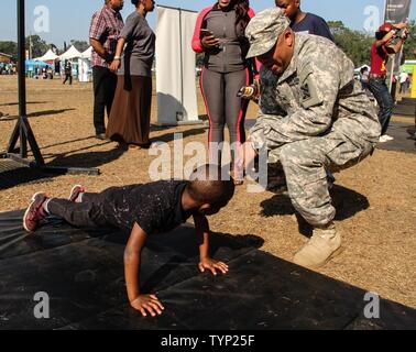 Armee Sgt. Marcus T. Williams, chemische Spezialist, 143d Sustainment Command (Auslandseinsätze), ruft ein Junge eine weitere Wiederholung während pushup Herausforderung durchgeführt 19.11.2016, an der GoArmy.com interaktive sowohl auf dem Messegelände liegt ausserhalb des Lagers Welt Stadion in Orlando, Fla. Williams, ein Eingeborener von Orlando, Eintritt in den aktiven Dienst und Soldaten, sich Zehntausende Fans an der Florida Klassiker, einer der größten Fußball-rivalitäten der Nation zwischen zwei historisch schwarze Hochschulen. Die Truppen verwaltet mehrere interaktive Herausforderungen, die Stärke der Lüfter getestet Stockfoto