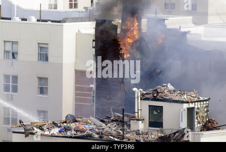 NYPD Feuerwehrmänner weiter zu einem Feuer in der Szene von 2 eingestürzten Gebäuden an 116 St und der Park Avenue in New York City am 13. März 2014 zu kämpfen. Mindestens 7 Menschen wurden getötet und mehrere weitere verletzt, wenn ein Leck in einer Gasleitung zu einer Explosion, die zwei Manhattan Gebäude am 12. März 2014 eingeebnet. UPI/John angelillo Stockfoto