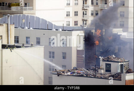 NYPD Feuerwehrmänner weiter zu einem Feuer in der Szene von 2 eingestürzten Gebäuden an 116 St und der Park Avenue in New York City am 13. März 2014 zu kämpfen. Mindestens 7 Menschen wurden getötet und mehrere weitere verletzt, wenn ein Leck in einer Gasleitung zu einer Explosion, die zwei Manhattan Gebäude am 12. März 2014 eingeebnet. UPI/John angelillo Stockfoto