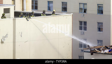 NYPD Feuerwehrmänner weiter zu einem Feuer in der Szene von 2 eingestürzten Gebäuden an 116 St und der Park Avenue in New York City am 13. März 2014 zu kämpfen. Mindestens 7 Menschen wurden getötet und mehrere weitere verletzt, wenn ein Leck in einer Gasleitung zu einer Explosion, die zwei Manhattan Gebäude am 12. März 2014 eingeebnet. UPI/John angelillo Stockfoto