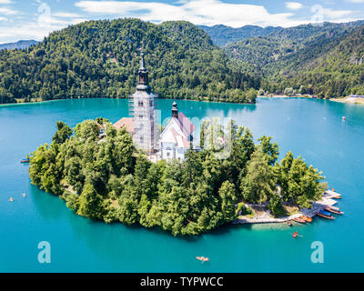 Luftaufnahme der Insel Bled oder Blejski otok, Maria Himmelfahrt Kirche mit einem Turm und spire, auf den Bleder See voller pletna Boote, b umgeben Stockfoto