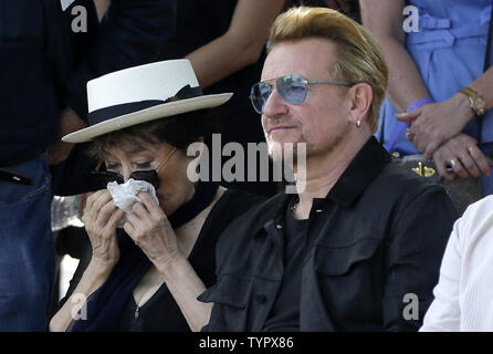 Bono von U2 sitzt mit Yoko Ono, der im Besitz eines Gewebes zu Gesicht, da sie sich auf eine musikalische Performance anhören, bevor Sie einen riesigen 24' x 10' Wandteppich zu Ehren John Lennon in der Gegenwart Amnesty International Generalsekretär Salil Shetty im Ellis Island Immigration Museum in New York City am 29. Juli 2015 vorstellen. Die Tapestry wurde durch Kunst für Amnesty Gründer Bill Shipsey beauftragt, als Dank an Ono für Amnesty International die Rechte an Coverversionen von Lennon's Post-Beatles Songs im Jahr 2004, so dass Amnesty über 5 Mio. $ in den Abgaben seit zu erhöhen. Bono, der Kante Stockfoto