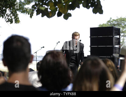 Bono von U2 Schritte einen Hügel hinunter zu seinem Stuhl, nachdem er Yoko Ono auf die Bühne vor der Enthüllung eines riesigen 24' x 10' Wandteppich zu Ehren John Lennon in der Gegenwart Amnesty International Generalsekretär Salil Shetty im Ellis Island Immigration Museum in New York City am 29. Juli 2015 zu sprechen. Die Tapestry wurde durch Kunst für Amnesty Gründer Bill Shipsey beauftragt, als Dank an Ono für Amnesty International die Rechte an Coverversionen von Lennon's Post-Beatles Songs im Jahr 2004, so dass Amnesty über 5 Mio. $ in den Abgaben seit zu erhöhen. Bono, Edge und mu Stockfoto