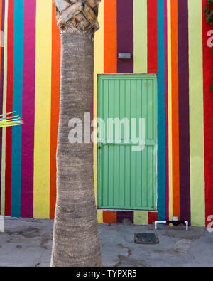 Mexikanische Haus mit bunt bemalten Streifen an der Wand mit einem grünen eiserne Tür n Mexiko und ein vor Stockfoto