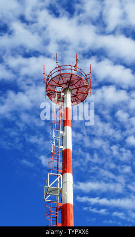 Telecom Tower für die drahtlose Übertragung von Radio, Handy oder Internet Signal. Telecom Mast in Rot und Weiß mit blauen Himmel und Wolken bemalt Stockfoto