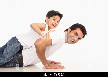 Vater tun Liegestütze mit Sohn auf seinem Rücken Stockfoto