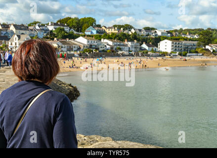 SAUNDERSFOOT, Pembrokeshire, Wales - AUGUST 2018: die Person auf der Hafenmauer mit Blick auf den Strand in Saundersfoot, West Wales. Stockfoto