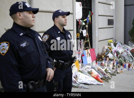 Zwei NYPD Polizisten stand Guard in der Nähe einer Gedenkstätte für Blumen, Notizen und Kerzen wächst außerhalb des Französischen Konsulats 3 Tage nach den Terroranschlägen in Paris am 16. November 2015 in New York City. Die Pariser Angriffen getötet, dass mindestens 129 Personen weiter Hausdurchsuchungen und Verhaftungen in Europa und Luftangriffen in Syrien am Montag zu veranlassen. Foto von John angelillo/UPI Stockfoto