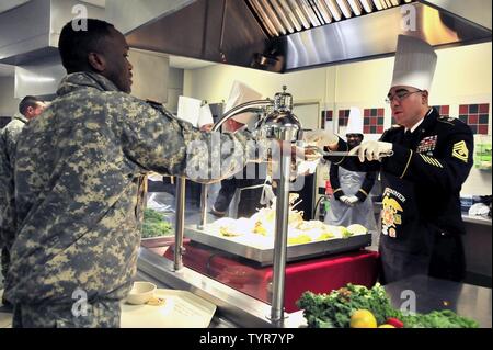 1 st. Sgt. Daniel Salinas der 226th Signal Unternehmen dient, eine Scheibe von der Türkei in einen 10 Mountain Division Sustainment Brigade Soldaten während der Brigade Thanksgiving Feier im Speisesaal November 22. Führungskräfte aus jedes Bataillon und Firma serviert den hungrigen Soldaten als Teil der Thanksgiving Feier. Stockfoto