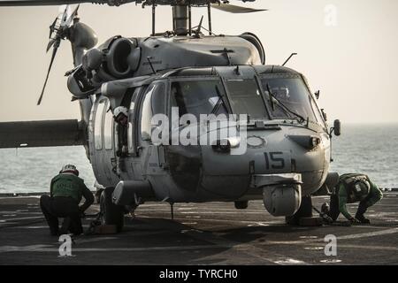 Golf (Nov. 22, 2016) Segler die Keile und Ketten entfernen von einem MH-60S Sea Hawk Hubschrauber zu den staubigen Hunde der Hubschrauber Meer Combat Squadron (HSC) 7 zugewiesen an Bord der schnellen Combat support ship USNS Arktis (T-AOE8). Arktis bereitgestellt wird Unterstützung der Koalition Seestreitkräfte Schiffe in den USA 5 Flotte Bereich der Operationen. Stockfoto