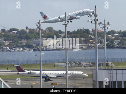 Eine Air Canada Flugzeug über einen Delta Airlines Flugzeug auf der Landebahn am Flughafen LaGuardia in New York City am 8. August 2016 in New York City bleibt. Delta begann wieder, aber immer noch erwarten, massive Streichungen und Verzögerungen nach nach einem computerstörschub Herunterfahren der Fluggesellschaft komplett an diesem Morgen. Foto von John angelillo/UPI Stockfoto