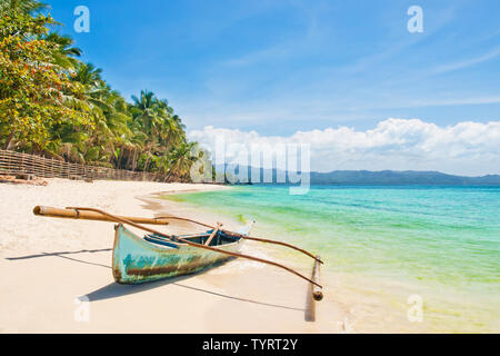 Alte traditionelle Outrigger Fischerboot auf weißen Sandstrand mit Palmen auf sonnigen Sommertag, Boracay Island, Philippinen Stockfoto