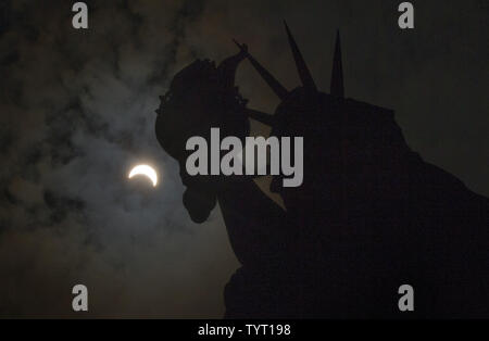 Eine partielle Sonnenfinsternis bewegt sich über den Himmel in der Nähe der Krone und der Fackel der Freiheitsstatue auf Liberty Island am 21. August 2017 in New York City. Heute ist die lange erwartete Sonnenfinsternis verdunkelte sich der Himmel von Oregon nach South Carolina wie der Mond zwischen Erde und Sonne. Das letzte Mal die aneinandergrenzenden Staaten der USA sah eine totale Sonnenfinsternis 1979 war, und der nächste wird nicht bis 2024. Foto von John angelillo/UPI Stockfoto