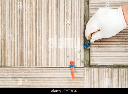 Die Hand eines Tile Orte einer Kunststoffschelle zwischen den Kacheln. Fliese Distanzstück. Stockfoto