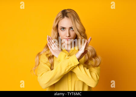 Frau, einen Anschlag mit verschränkten Armen. Auf grauem Hintergrund. Stockfoto