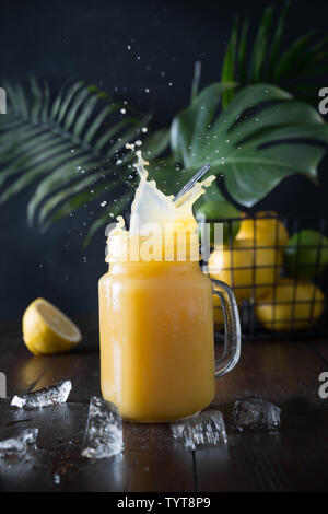 Splush Sommer Früchte smoothies oder Saft mit Banane, Kalk auf dunklen tropischen Holz- Hintergrund. Close Up. Stockfoto