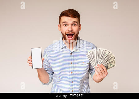 Überrascht tausendjährigen Kerl mit Geld und Handy Stockfoto