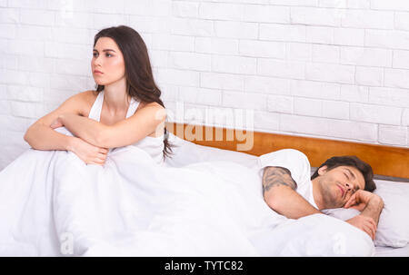 Unglückliche junge Frau mit Schlafstörungen im Bett sitzen Stockfoto