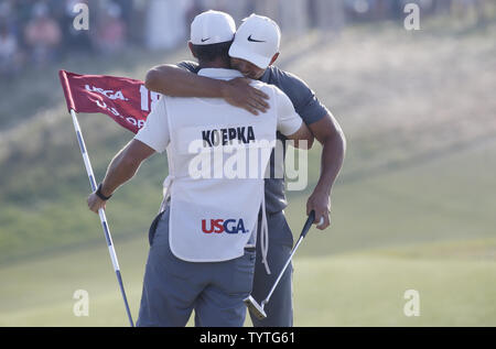 Bäche Koepka Umarmungen caddie Richard Elliot auf der 18 nach dem Gewinn der 118 U.S. Open Championship in Shinnecock Hills Golf Club in Southampton, New York am 17. Juni 2018. Koepka gewann die Meisterschaft mit einer Punktzahl von 1 über Par Tommy Fleetwood aus England werden nur die sechste Spieler bis 63 in einem U.S. Open schießen. Foto von John angelillo/UPI Stockfoto