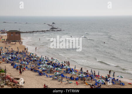 Tel Aviv, Israel - 13. April 2019: Schöne Aussicht auf einem überfüllten Strand in einer modernen Stadt während einer bewölkt und sonnig. Stockfoto