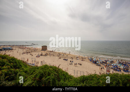 Tel Aviv, Israel - 13. April 2019: Schöne Aussicht auf einem überfüllten Strand in einer modernen Stadt während einer bewölkt und sonnig. Stockfoto