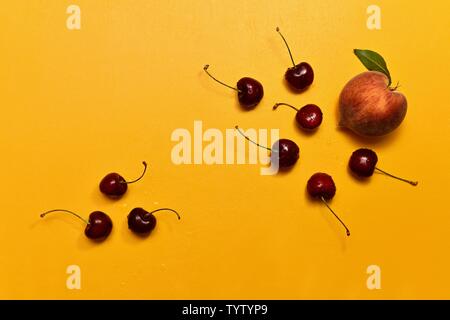 Ein Pfirsich mit einem Blatt und sechs roten Kirschen mit Stengel einer Gruppe und drei süße Kirschen mit einer anderen Gruppe auf einem Richtfest Hintergrund. Stockfoto