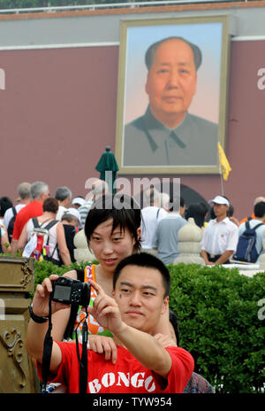Ein junges Paar nimmt Ihre eigenen Bild mit Ihrer Digitalkamera vor dem Portrait des ehemaligen Vorsitzenden Mao Zedong am Eingang zur Verbotenen Stadt in Peking am 4. August 2008. Chinesischen und ausländischen olympischen Besucher strömten zu den touristischen Gebieten in der Nähe der Verbotenen Stadt, dem Tiananmen-Platz angrenzenden ist vor Beginn der Olympischen Spiele zu starten am 8. August. (UPI Foto/Pat Benic) Stockfoto