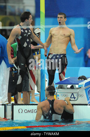 Die USA Michael Phelps und Mannschaftskamerad Garrett Weber-Gale (L) jubeln wie Jason Lezak (Wasser) kommt an der Oberfläche der Damen 4x100 m Staffel finale bei den National Aquatics Center bei den Olympischen Sommerspielen in Peking am 11. August 2008. Lezak kam von hinten und gewann ein dramatischer Sieg für die Vereinigten Staaten Mannschaft, das Setzen der Weltrekordzeit von 3:08.24. (UPI Foto/Pat Benic) l Stockfoto