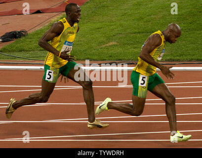 Jamaikas Usain Bolt (L) schreit Teamkollegen Asafa Powell nach ihm übergibt den Staffelstab für die letzte Etappe der Männer 4x100m Staffel finale während der Olympischen Spiele 2008 in Beijing, 22. August 2008. Das Team gewann den Gold und einen neuen Weltrekord mit einer Zeit von 37.10. Trinidad und Tabago Silber mit Japan erfassen Bronze. (UPI Foto/Stephen Rasierer) Stockfoto