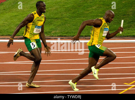 Jamaikas Usain Bolt (L) schreit Teamkollegen Asafa Powell nach ihm übergibt den Staffelstab für die letzte Etappe der Männer 4x100m Staffel finale während der Olympischen Spiele 2008 in Beijing, 22. August 2008. Das Team gewann den Gold und einen neuen Weltrekord mit einer Zeit von 37.10. Trinidad und Tabago Silber mit Japan erfassen Bronze. (UPI Foto/Stephen Rasierer) Stockfoto