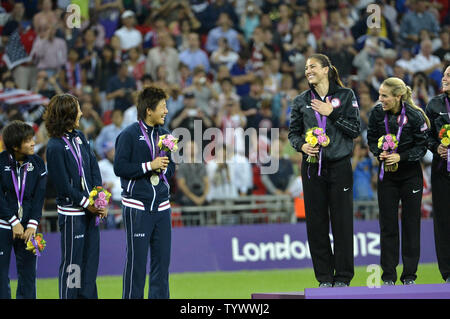 United States Team Mitglieder (R), einschließlich goalie Hoffnung Solo (3., R) Grüße Japan's Team bei der Siegerehrung, wo sie ihre Goldmedaillen für eine 2-1 über Japan bei der Fussball-WM der Frauen im Wembley Stadium gewinnen bei den Olympischen Sommerspielen 2012, 9. August 2012, in London, England. UPI/Mike Theiler Stockfoto