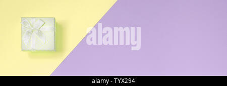 Kleiner gelber Geschenkbox liegen auf Textur Hintergrund der Mode pastell Gelb und Violett Farben Papier in minimalen Begriff. Stockfoto