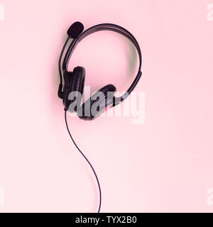 Schwarz Kopfhörer liegt auf einem farbenfrohen Pastelltönen rosa Hintergrund. Musik hören. Flach Top View Stockfoto