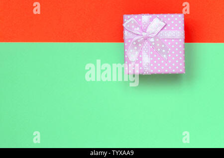 Kleine rosa Geschenkkarton liegen auf Textur Hintergrund der Mode pastell Farben Türkis und Rot Papier in minimalen Begriff. Stockfoto