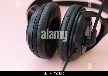 Schwarz Kopfhörer liegt auf einem farbenfrohen Pastelltönen rosa Hintergrund. Musik Konzept Stockfoto