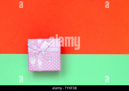 Kleine rosa Geschenkkarton liegen auf Textur Hintergrund der Mode pastell Farben Türkis und Rot Papier in minimalen Begriff. Stockfoto