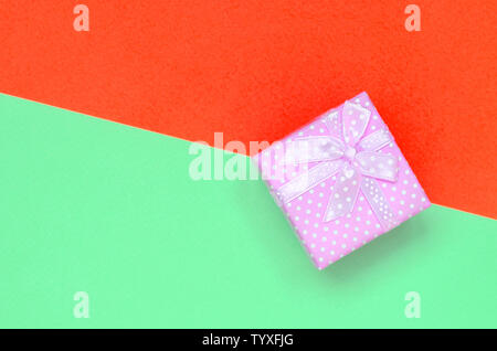 Kleine rosa Geschenkkarton liegen auf Textur Hintergrund der Mode pastell Farben Türkis und Rot Papier in minimalen Begriff. Stockfoto