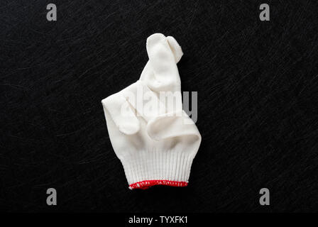 Weißer Handschuh mit Geste der Finger auf schwarzem Hintergrund gekreuzt Stockfoto