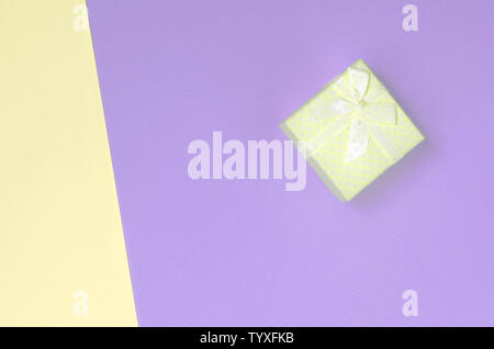 Kleiner gelber Geschenkbox liegen auf Textur Hintergrund der Mode pastell Gelb und Violett Farben Papier in minimalen Begriff. Stockfoto