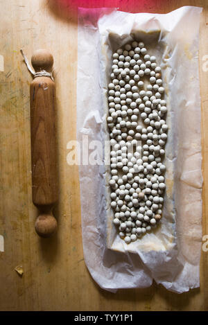 Keramik Backbohnen in tart Zinn, Ansicht von oben, auf einem Holzbrett mit Küche Roller und Zutaten. Stockfoto