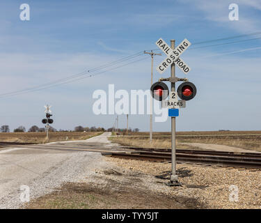 Bahnübergang mit Warnzeichen und Kontrolllampen auf einer Landstraße in der Landschaft Stockfoto