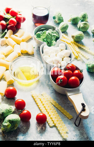 Tomaten, Basilikum und Mozzarella. Lebensmittelzutaten Muster mit mozarella Käse Kugeln und frische Basilikumblätter, runde Cherry Tomaten, mit Pasta und Wein, Stockfoto