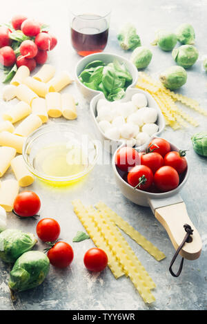 Tomaten, Basilikum und Mozzarella. Lebensmittelzutaten Muster mit mozarella Käse Kugeln und frische Basilikumblätter, runde Cherry Tomaten, mit Pasta und Wein, Stockfoto