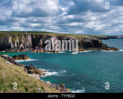 Geneigte Schichten aus rotem Sandstein sedimentäre Gestein Felsen aus der kambrischen Periode an der St nicht Bucht auf der Pembrokeshire Coastal Path, in der Nähe von St David's Stockfoto