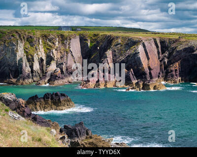 Geneigte Schichten aus rotem Sandstein sedimentäre Gestein Felsen aus der kambrischen Periode an der St nicht Bucht auf der Pembrokeshire Coastal Path, in der Nähe von St David's Stockfoto