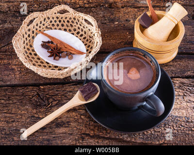Tasse Schokolade mit Gewürzen (Zimt, Nelken und Anis) und mörser auf einem authentischen alten Tisch Stockfoto