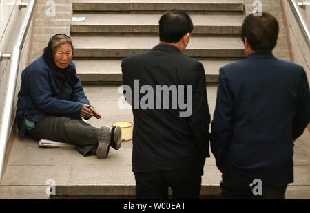 Eine alte Frau bittet Geschäftsleute für Geld auf den Straßen von Peking, China, am 28. März 2006. Ohne eine nationale Sozialsystem oder soziale Netz, die in der entsetzlichen Notwendigkeit der medizinischen hekp zu fangen, viele verkrüppelte und Chinesische Behinderte sind gezwungen, für sich selbst zu sorgen und in der Regel landen auf der Straße. Eine große Sorge unter den Chinesischen litt unter den schwierigen wirtschaftlichen Reformen in ein paar Jahren geschlossen und viele Staatsbetriebe ist das virtuelle Abschaffung der staatlichen Sozialsysteme, die einst, nachdem sie von der Geburt bis zum Tod. (UPI Foto/Stephen Rasierer) Stockfoto